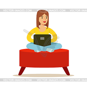 Счастливый молодая женщина сидит в красном пуф и используя - клипарт