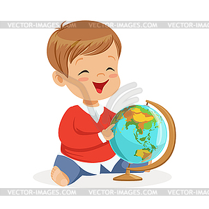 Smiling little boy sitting and playing with globe. - vector image