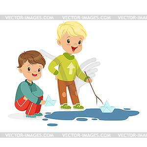 Cute little boys playing with paper boats in water - vector clipart